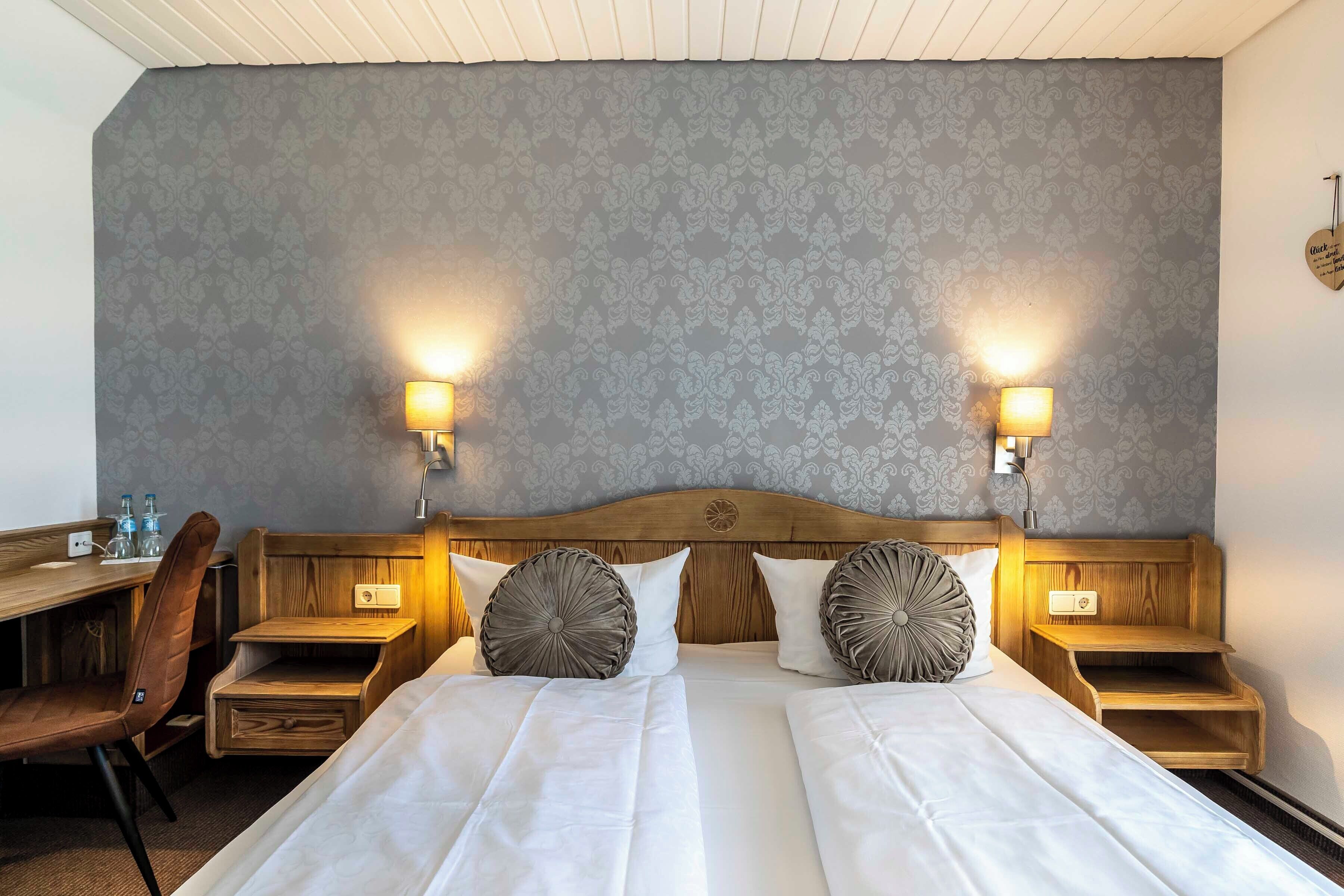 A double bed with two nightstands, a wooden desk, and a chair in a hotel room.