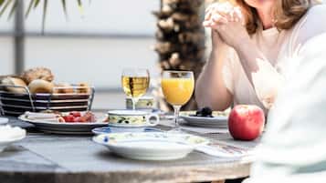 Een ontbijttafel met borden vol eten, een glas sinaasappelsap en een glas witte wijn.