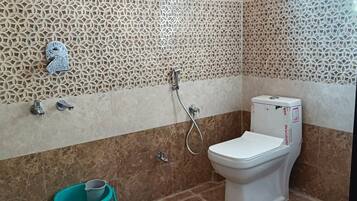 A bathroom with a toilet, a shower, and a sink.