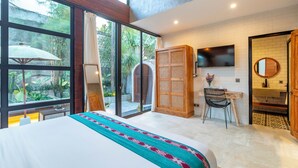 A bedroom with a large bed, a desk, a chair, and a TV. - Villa Indra Pererenan by Orivista (Canggu)