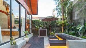 A modern outdoor patio with a wooden deck, seating areas, and potted plants. - Villa Indra Pererenan by Orivista (Canggu)