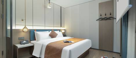 A modern hotel room with a large bed, bedside tables, a wardrobe, and a hanging coat rack.