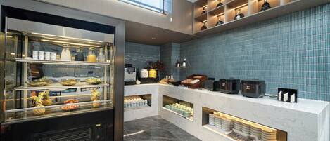 Um balcão de café da manhã moderno com refrigerador, estação de café e painel de azulejos azuis.