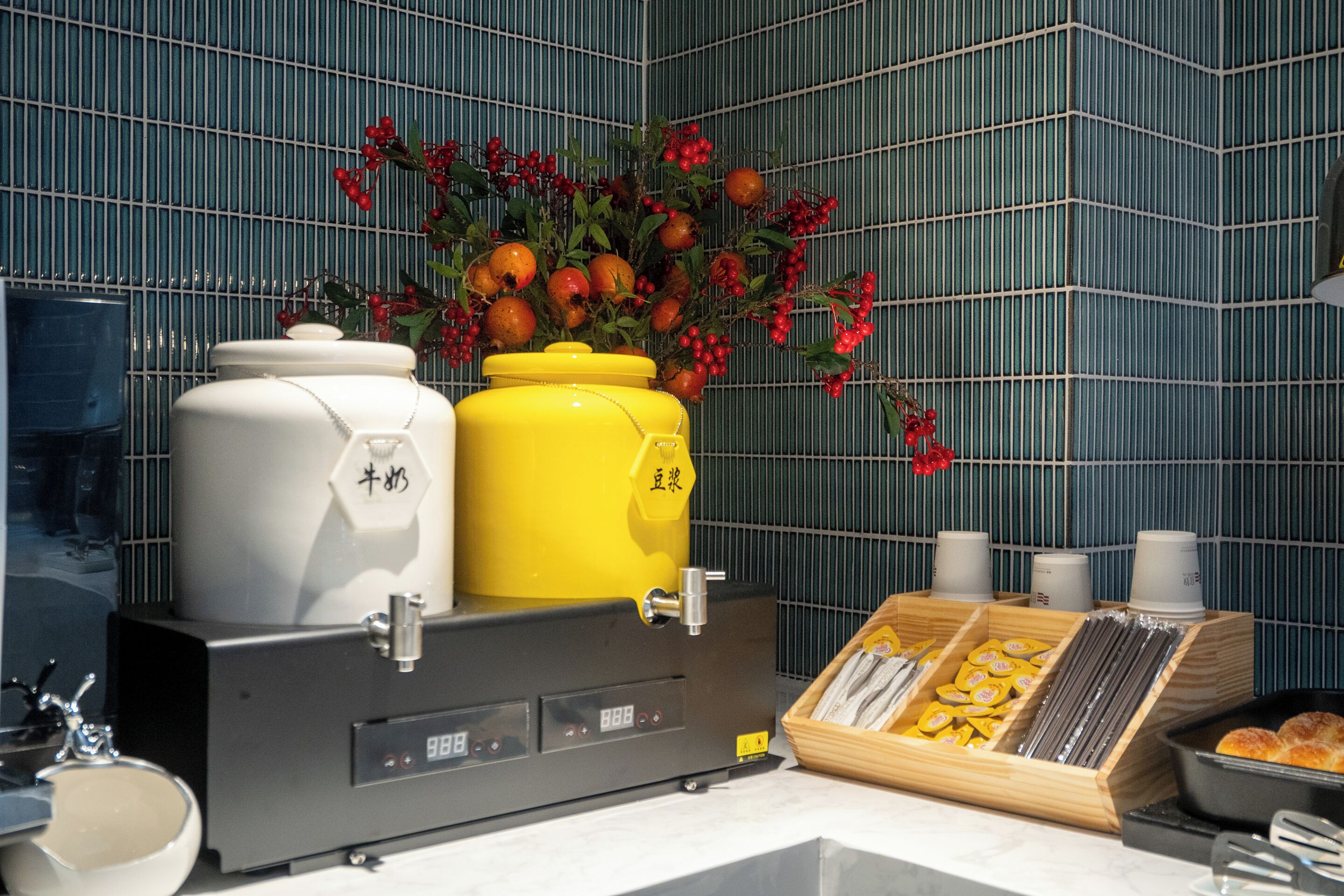 Un coin cuisine équipé d’une machine à café, d’un récipient jaune et d’un plateau de viennoiseries.