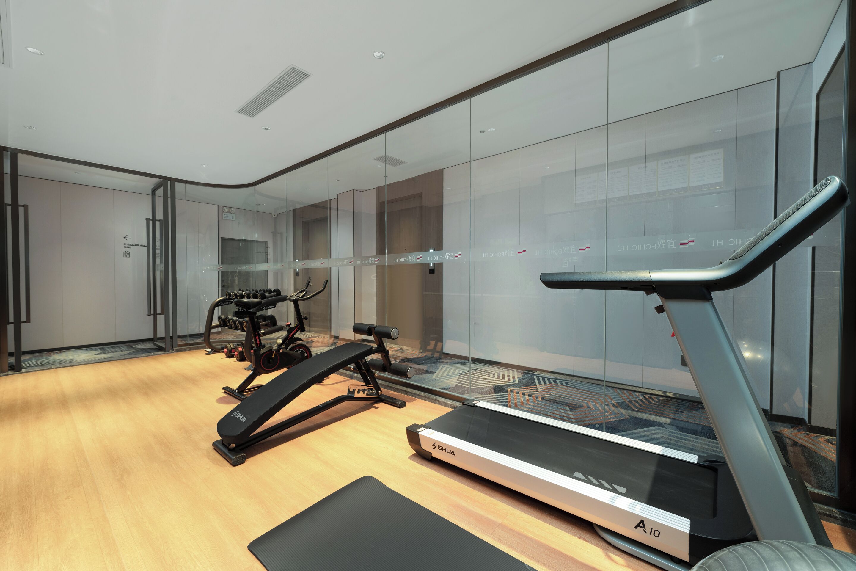 A modern gym with a treadmill, elliptical, and weight machines.