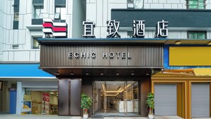 A hotel entrance with a modern facade, glass doors, and potted plants. - YiZhi HotelShangxiajiu Pedestrian Stree (Guangzhou)