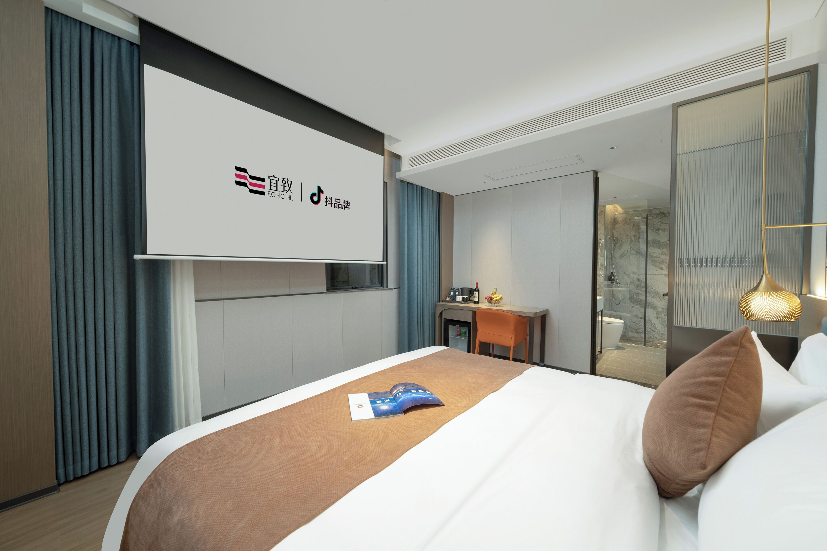 Habitación de hotel con cama, escritorio, minibar y baño con ducha de vidrio.