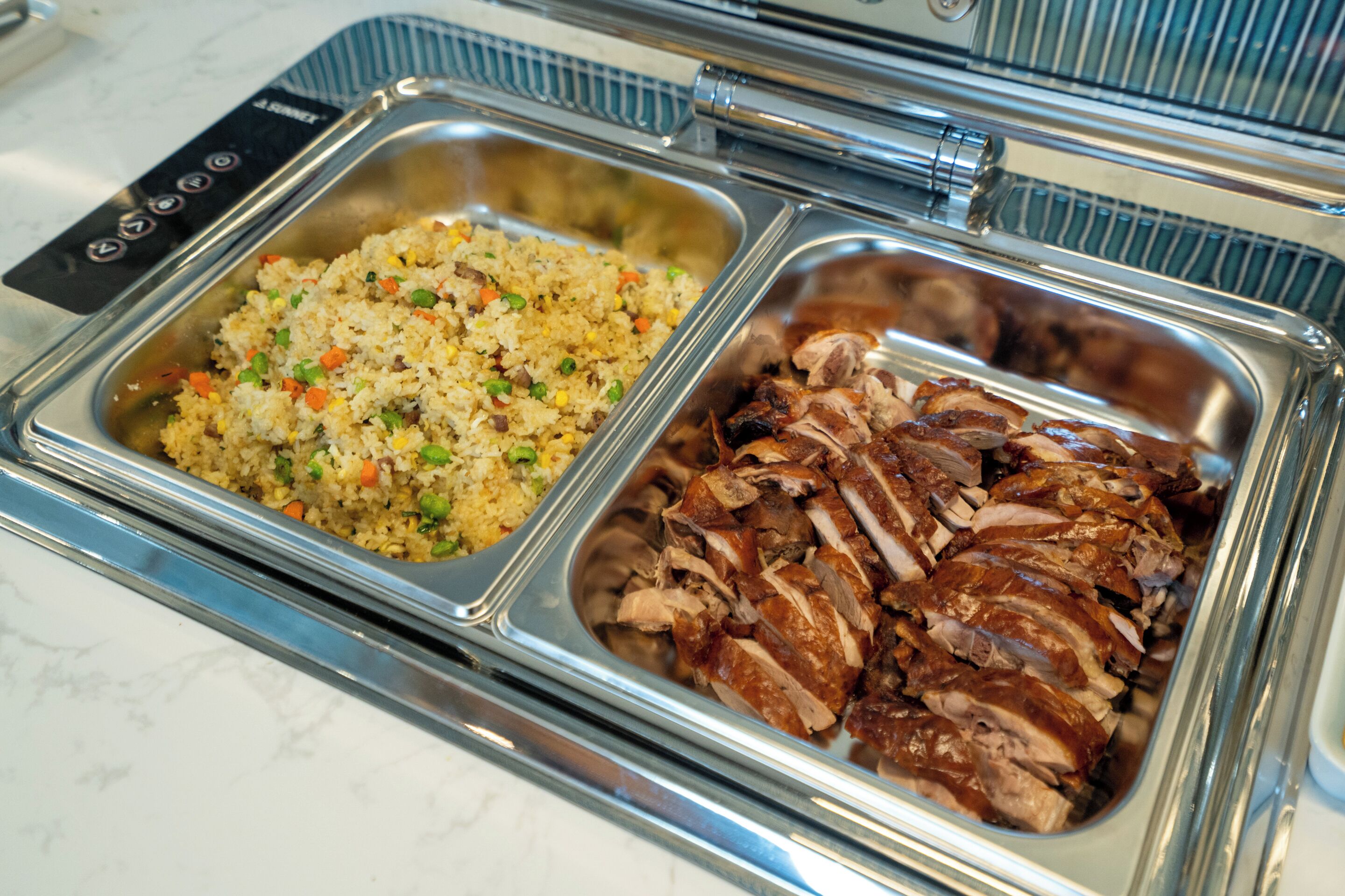 A buffet with fried rice and sliced meat.