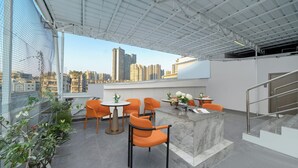 A rooftop terrace with orange chairs, a marble counter, and potted plants. - YiZhi HotelShangxiajiu Pedestrian Stree (Guangzhou)