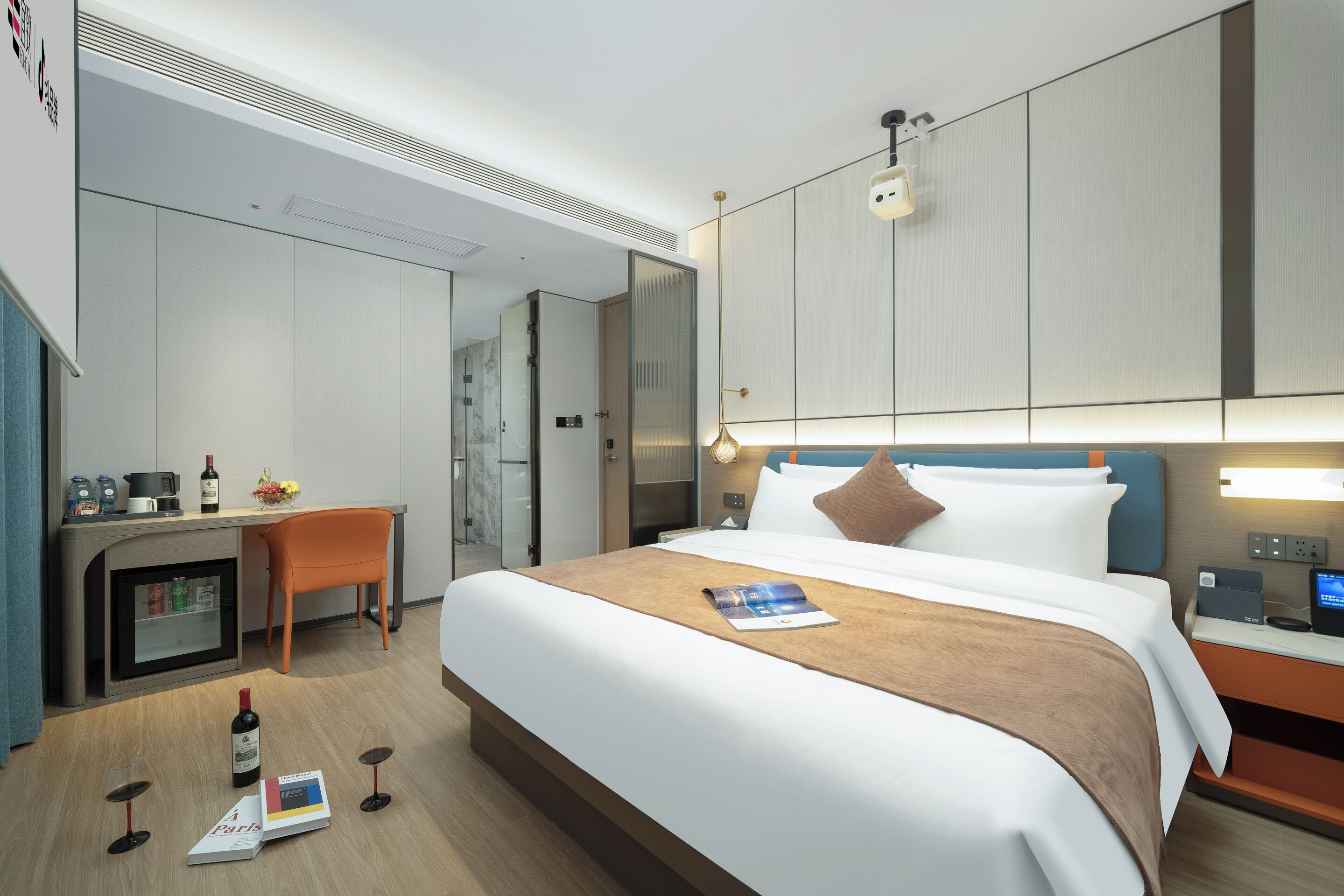 Una moderna camera d'albergo con un letto, una scrivania, una sedia e un minibar.