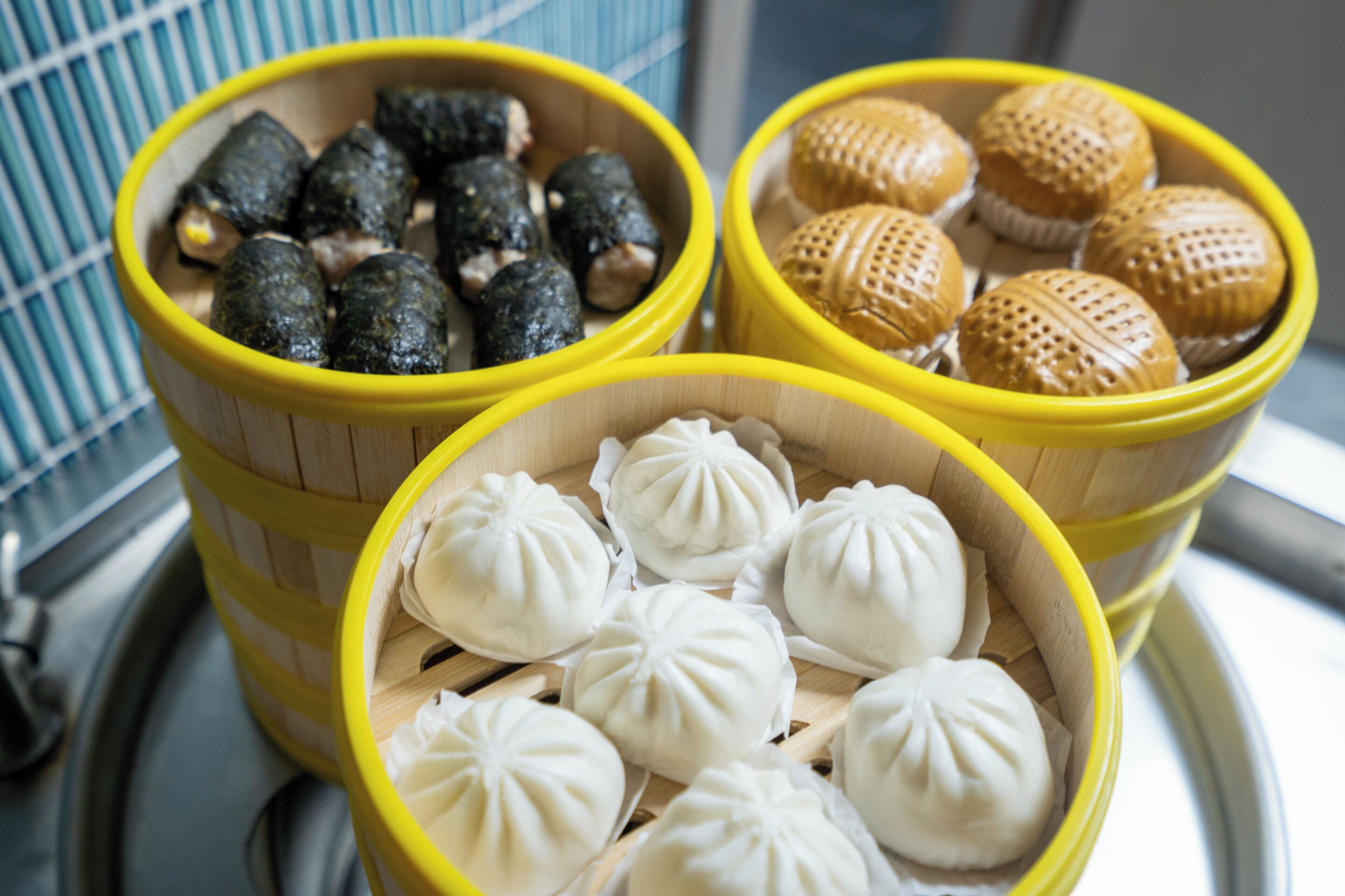 Three bamboo steamers with different types of dumplings.
