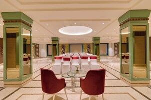 Amplia habitación con una zona de estar central, una mesa de vidrio y sillas rojas.