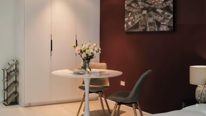 A modern room with a white wardrobe, a round table with chairs, a vase of flowers, and a painting on the wall. - Centraltique Veranda Living (Hanoi)