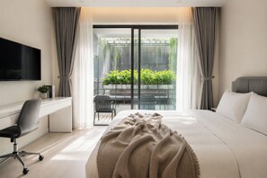 A modern hotel room with a bed, desk, chair, and a balcony with plants. - Centraltique Veranda Living (Hanoi)