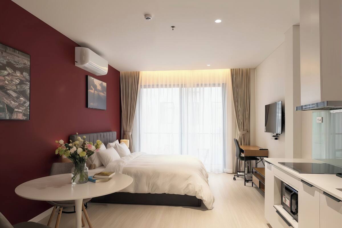 Una camera d'albergo moderna con un letto, una scrivania, una TV e angolo cottura.