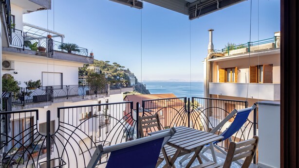 A balcony with a view of the sea, a table with chairs, and a railing. - Capo Sereno (Sorrento)