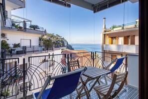 A balcony with a view of the sea, a table with chairs, and a railing. - Capo Sereno (Sorrento)
