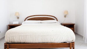 A neatly made bed with a white bedspread and two bedside lamps on wooden nightstands. - Capo Sereno (Sorrento)