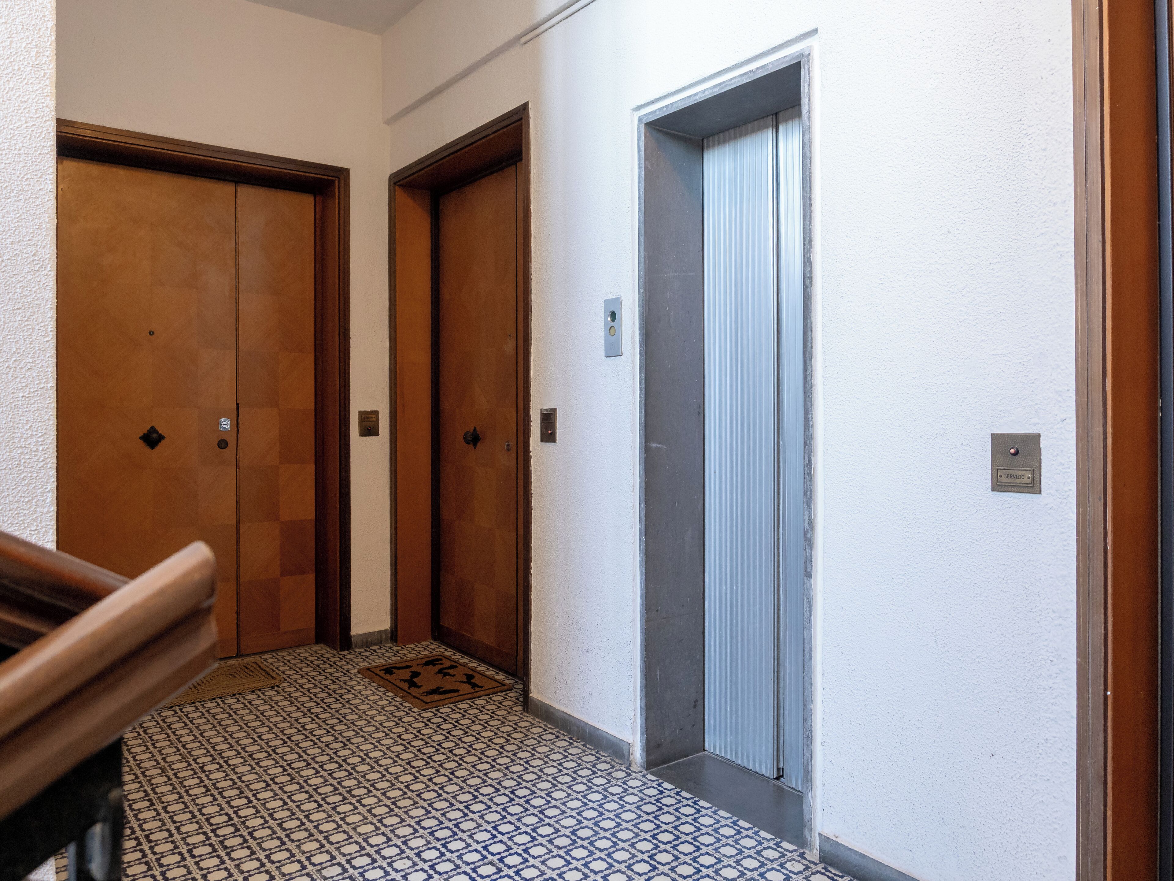 Un pasillo con dos puertas de madera y una puerta de ascensor metálica.