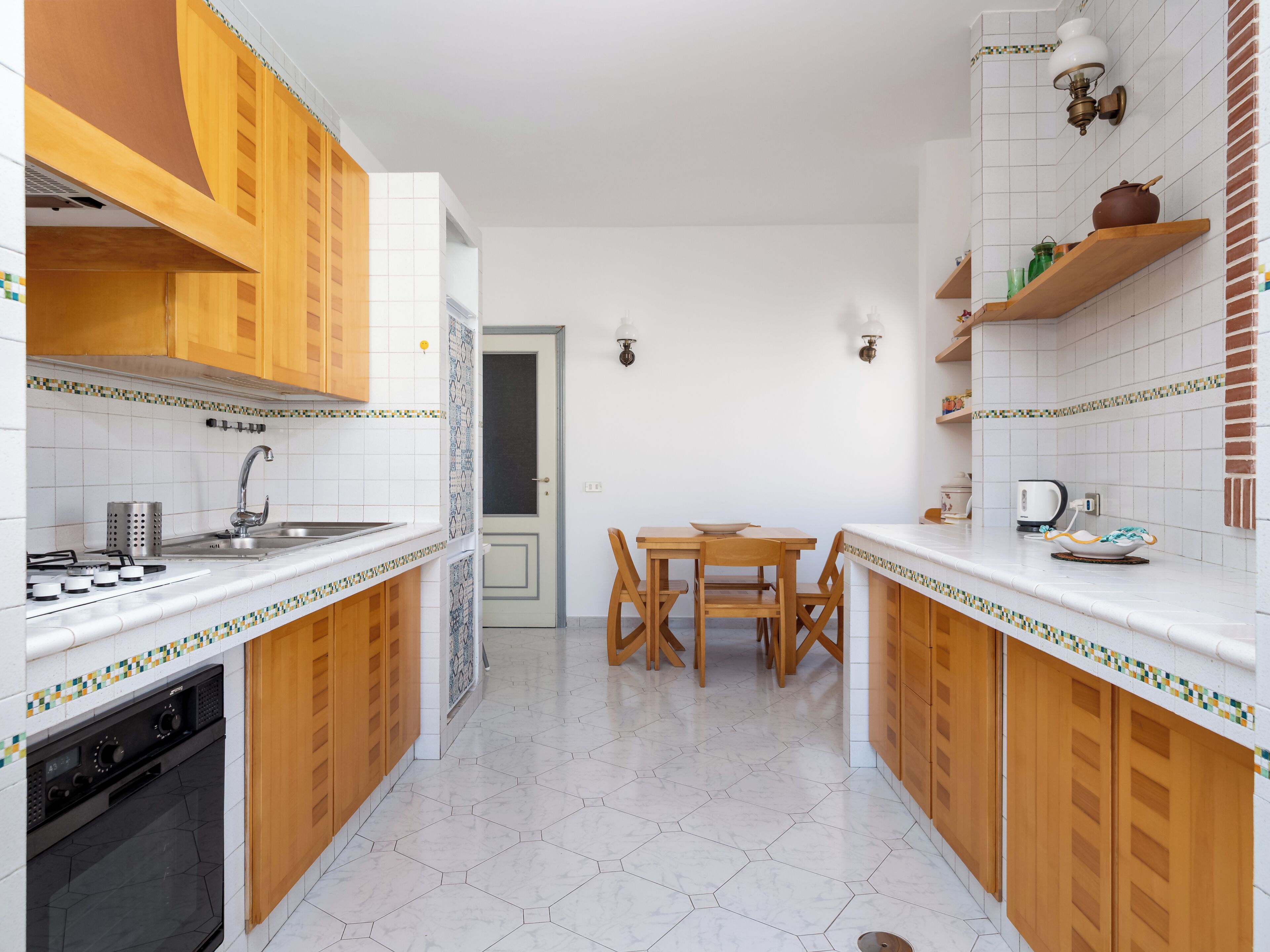Een moderne keuken met houten kastjes, een eettafel en een inbouwoven.