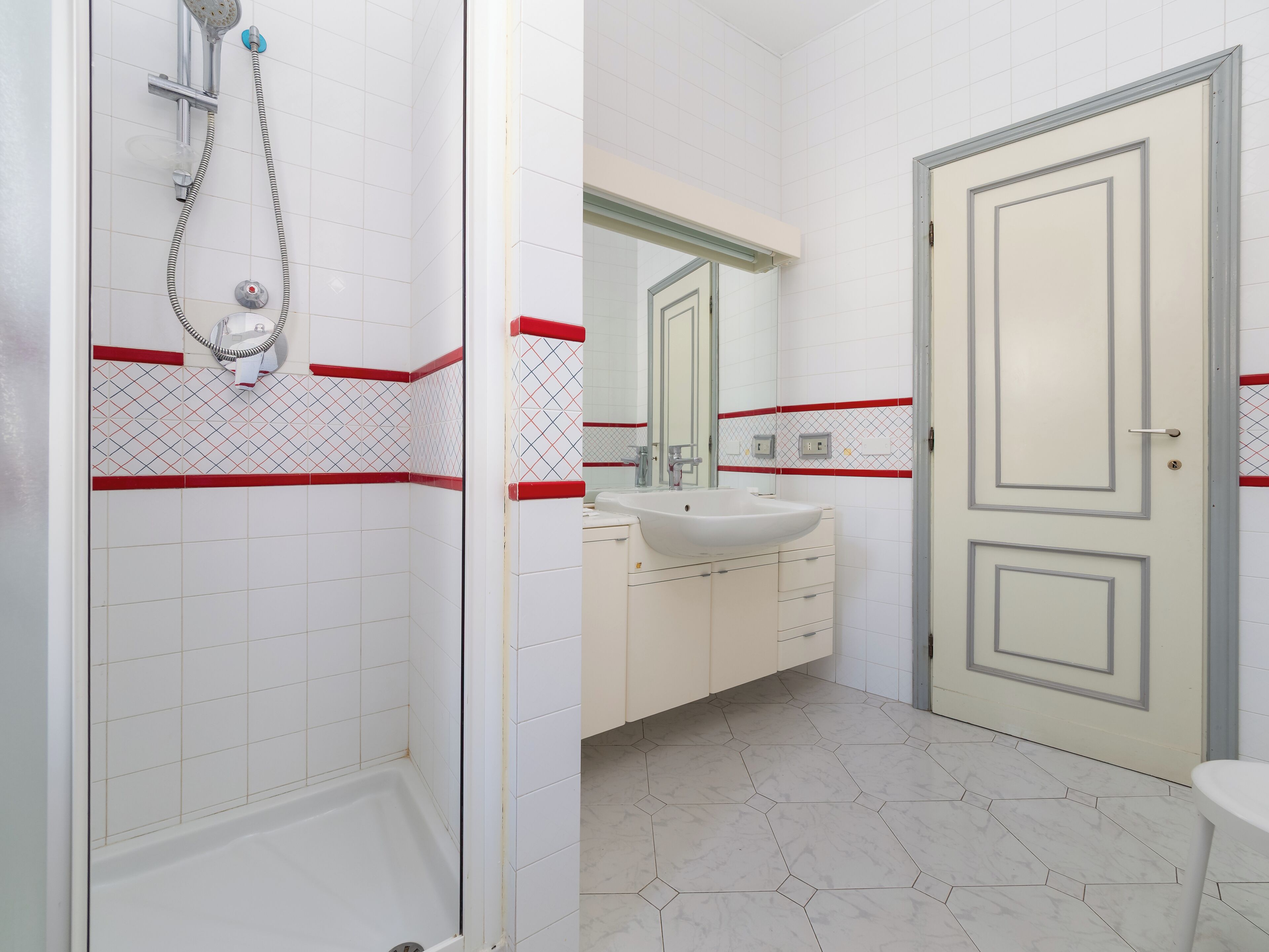 Une salle de bain avec une douche, un lavabo et un miroir.