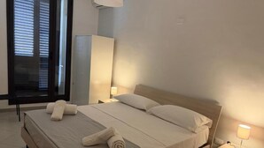 A neatly made bed with white linens and towels, a bedside lamp, and a nightstand with a remote control. - Comfort, style and views: your perfect stay at Civico24rooms (Caltagirone)