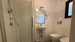 A bathroom with a glass shower enclosure, a white sink, a toilet, and a bidet. - Comfort, style and views: your perfect stay at Civico24rooms (Caltagirone)