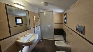 A modern bathroom with a sink, bidet, and mirror. - An elegant retreat overlooking the city of mosaics (Caltagirone)