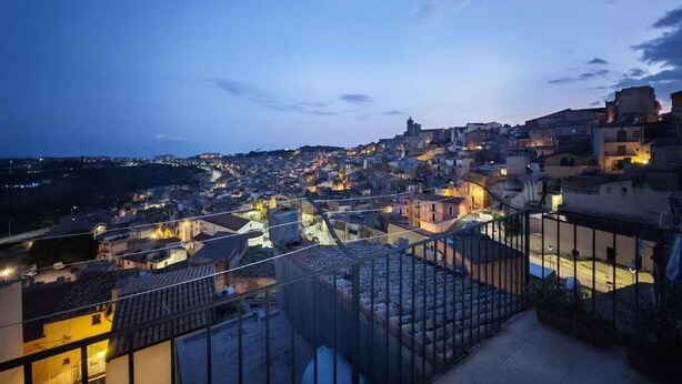 A nighttime view of a densely packed urban area with buildings and streets illuminated by artificial lights. - An elegant retreat overlooking the city of mosaics (Caltagirone)