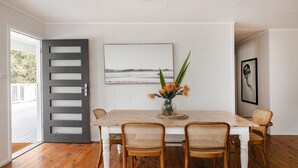 Ein Essbereich mit einem Holztisch, Korbstühlen, einem Blumenvasen und Bildern an der Wand.
