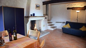 A cozy room with a fireplace, a sofa, a dining table with chairs, and a blue wardrobe. - Agriturismo Alla Vecchia Quercia vacation apartment "Cagli" for 2 persons (Pergola (PU))