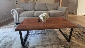 A living room with a grey sofa, a wooden coffee table, and a rug. - Stockbridge Home w/ Master Suite on the Main (Stockbridge)