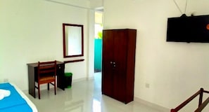Una habitación con cama, escritorio, armario y televisor.
