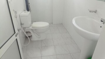 Un baño con inodoro, lavabo y suelo de baldosas.