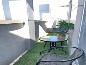 A small outdoor area with artificial grass, a round table, and two wicker chairs. - Ansan City View Apartment with Netflix (Ansan-si)