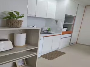 A compact kitchen with white cabinets, a toaster, a sink, and a potted plant. - Ansan City View Apartment with Netflix (Ansan-si)