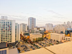 A cityscape with high-rise buildings, a parking lot, and autumn foliage. - Ansan City View Apartment with Netflix (Ansan-si)