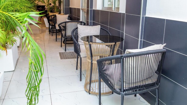 A corridor with a tiled floor, black and white walls, and wicker chairs. - Sukoon Nyali Suites (Mombasa)