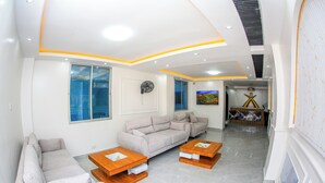 A modern living room with a sofa set, two wooden coffee tables, and a flat-screen TV. - Sukoon Nyali Suites (Mombasa)