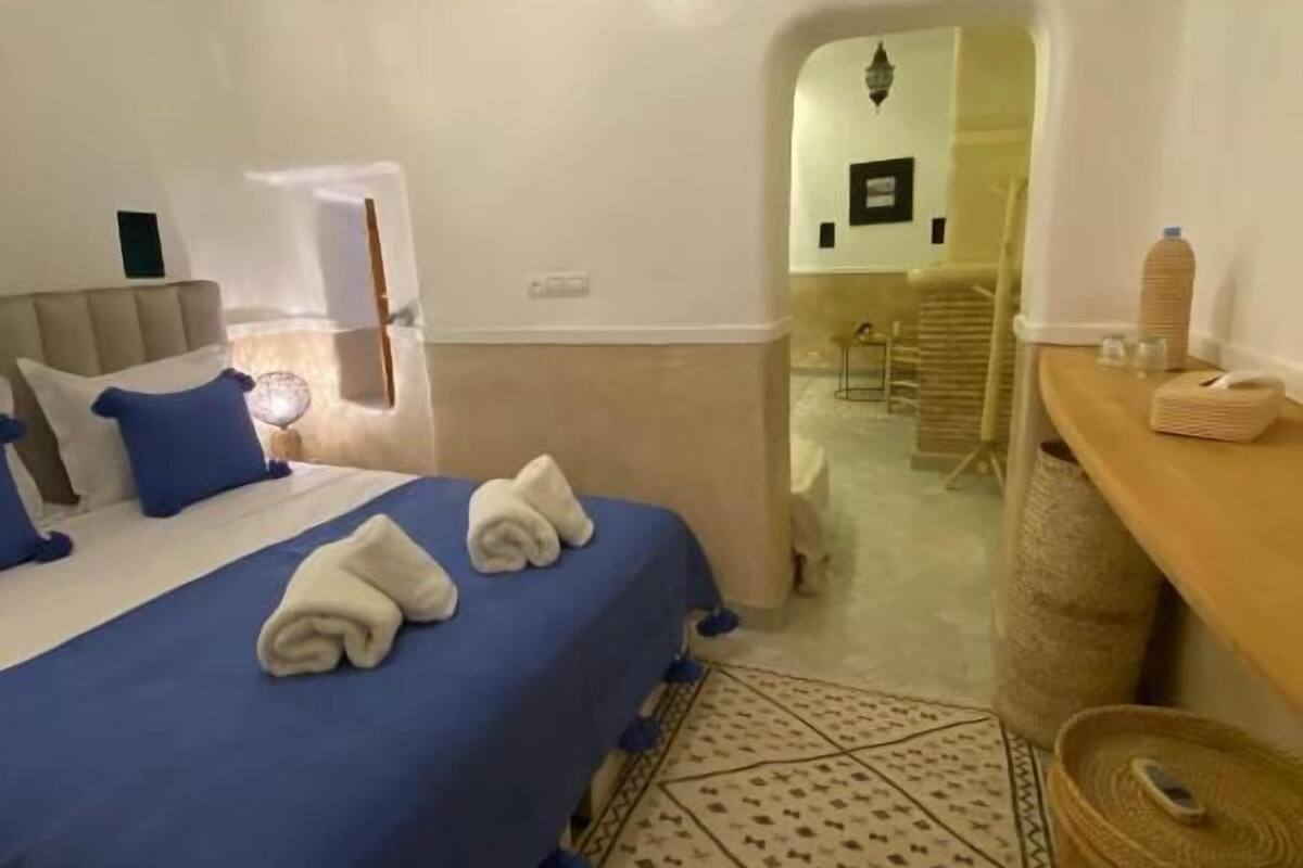 Una camera d'albergo con un letto, una scrivania, una sedia, un condizionatore d'aria e un pavimento decorato.