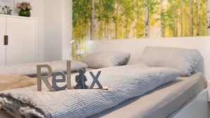Une chambre à coucher avec un lit, des oreillers, un mur orné d’une fresque sur le thème de la nature, une petite statue et un tableau encadré.
