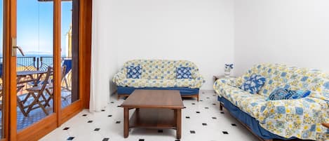 Una habitación con dos sofás, una mesa de madera y vista al mar a través de un ventanal.