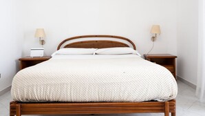 A bed with a wooden frame, white bedding, two bedside lamps, and a small bedside table with a lamp. - Capo Sereno - Large & Bright apt with terrace (Sorrento)