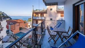 A balcony with a view of the sea, a pool, and a dining area with outdoor furniture. - Capo Sereno - Large & Bright apt with terrace (Sorrento)