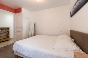 Une chambre à coucher avec un lit, une table de chevet en bois, une armoire et une porte.