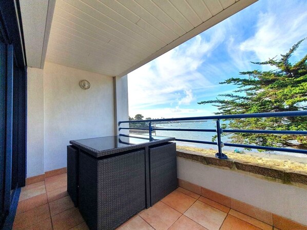 Un balcon avec vue sur la mer, une balustrade et une petite table.