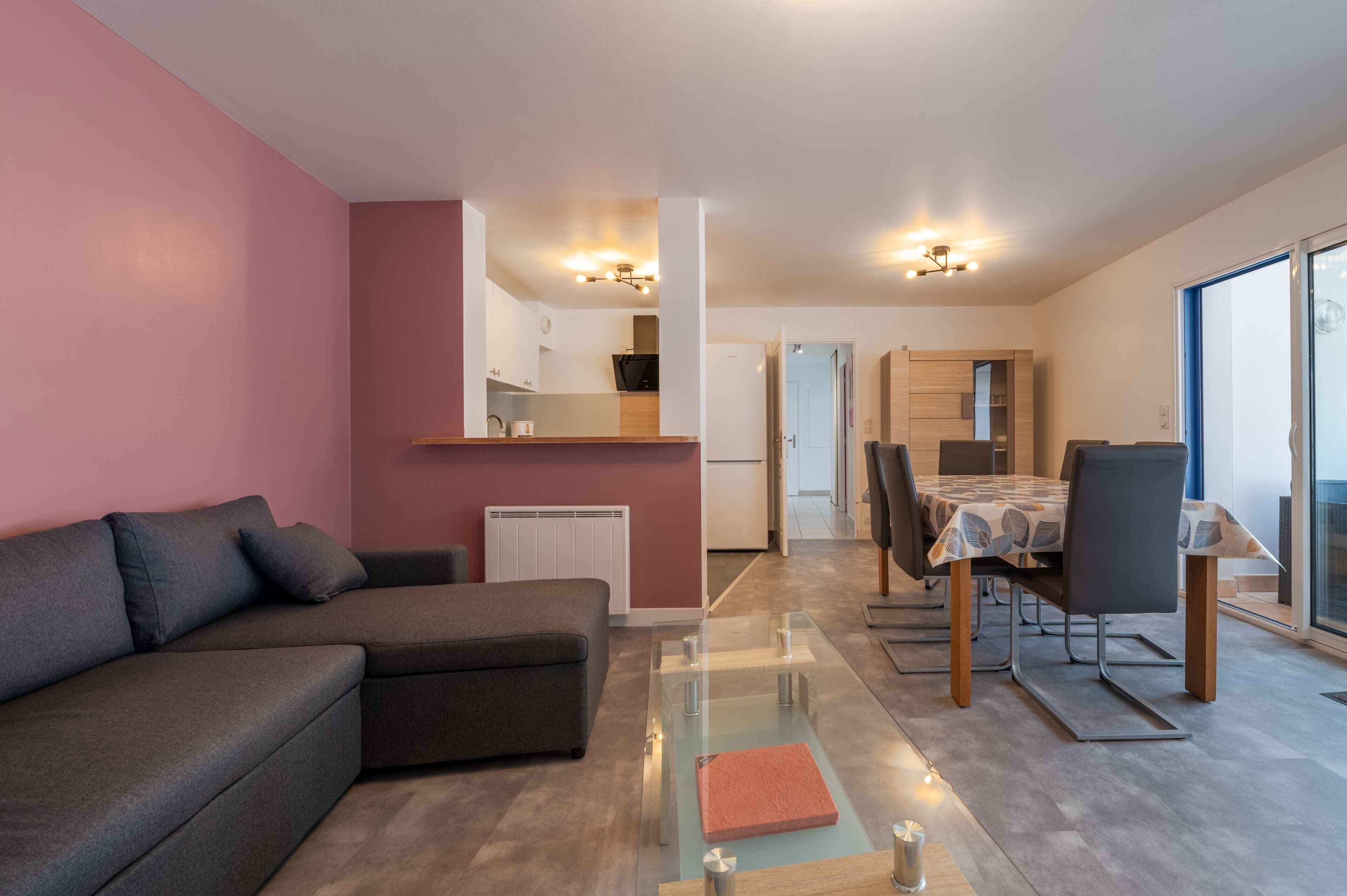 A modern living room with a sofa, a glass coffee table, and a dining area with a table and chairs.