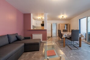 Una sala de estar moderna con un sofá, una mesa de centro de vidrio y un comedor con una mesa y sillas.
