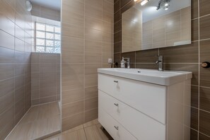 Une salle de bain avec une douche, un lavabo et un miroir.