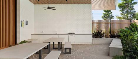 An outdoor patio area with stone flooring, a wooden ceiling, and a white brick wall.